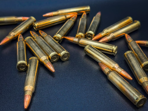 bullets - North American Bow Hunter Assorted rifle bullets with copper tips scattered on a dark blue surface.